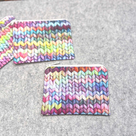 Colorful knitted pouches on a gray surface
