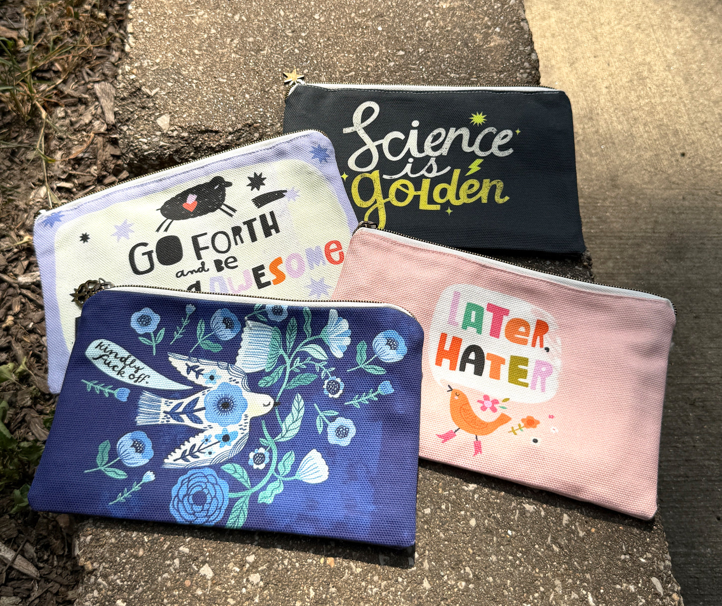 Four pouches with different designs and text on a textured surface.