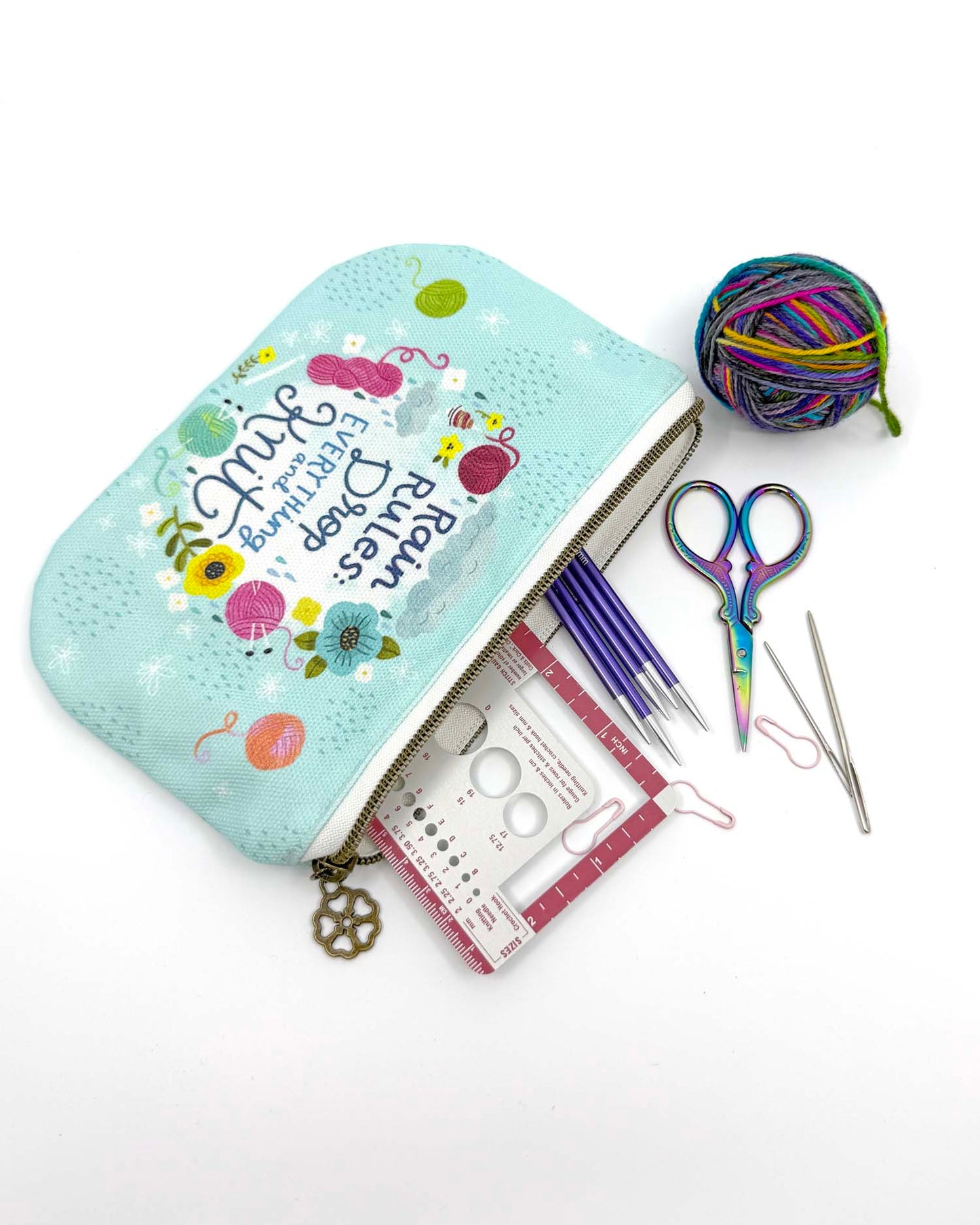 blue green canvas zippered pouch printed with yarn and flowers that says "rain rules drop everything and knit" 