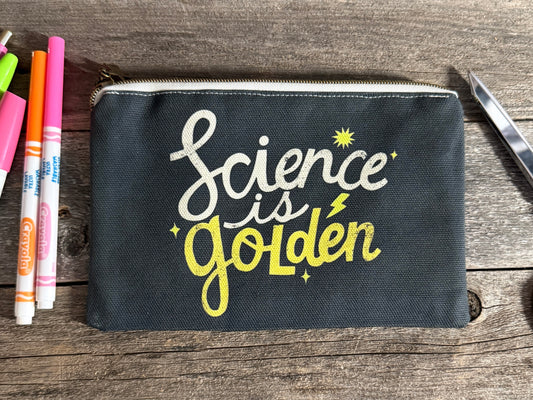 Black pouch with 'Science is Golden' text on a wooden surface with markers.