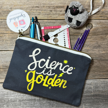 Black pouch with 'Science is Golden' text on a wooden surface with stationery items.